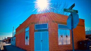 A small brick building with a blue door and windows, a stop sign, and a street sign reading "CROMWELL AVE." - Cozy & Historic | Old Bakery Building Close to Downtown (Albuquerque)