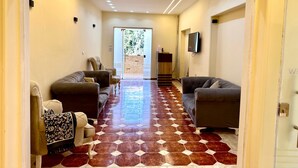 A hallway with two sofas, a patterned throw, and a tiled floor. - Golf Pyramids View (Giza)
