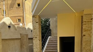 A courtyard with a staircase leading to a covered entrance, surrounded by stone walls and potted plants. - Golf Pyramids View (Giza)
