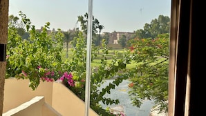A view from a window overlooking a garden with a water feature, trees, and buildings in the background. - Golf Pyramids View (Giza)