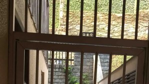 Une entrée fermée par un portail donne sur une cour intérieure, où un escalier en pierre mène à un bâtiment.