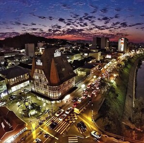 Ein historisches Gebäude mit einem markanten Turm und der Beschriftung 'HAVAN', nahe einem belebten Ufer mit einer Straße und geparkten Autos.