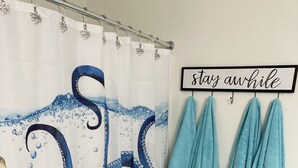 Un baño con cortina de ducha de diseño de pulpo, un inodoro y un perchero con toallas.