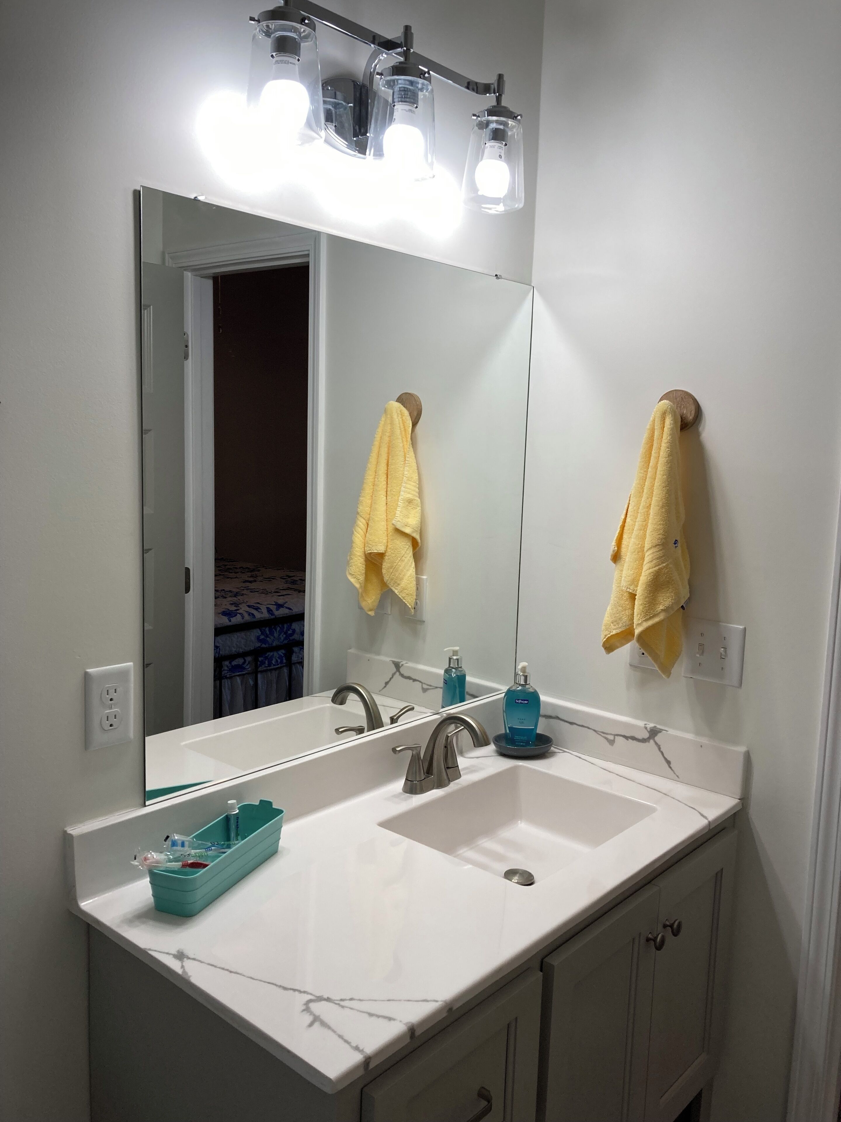 Une salle de bain avec un lavabo blanc, un miroir et un porte-serviettes avec des serviettes jaunes.