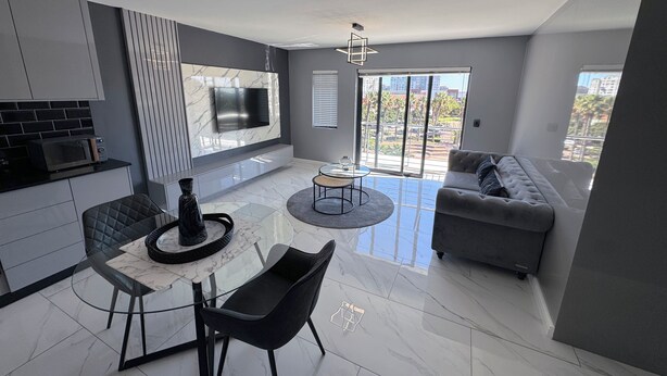 A modern living space with a kitchen, dining area, and a sofa. - Knightsbridge Luxury Apartments Century City by Vvip Bookings  (Cape Town)