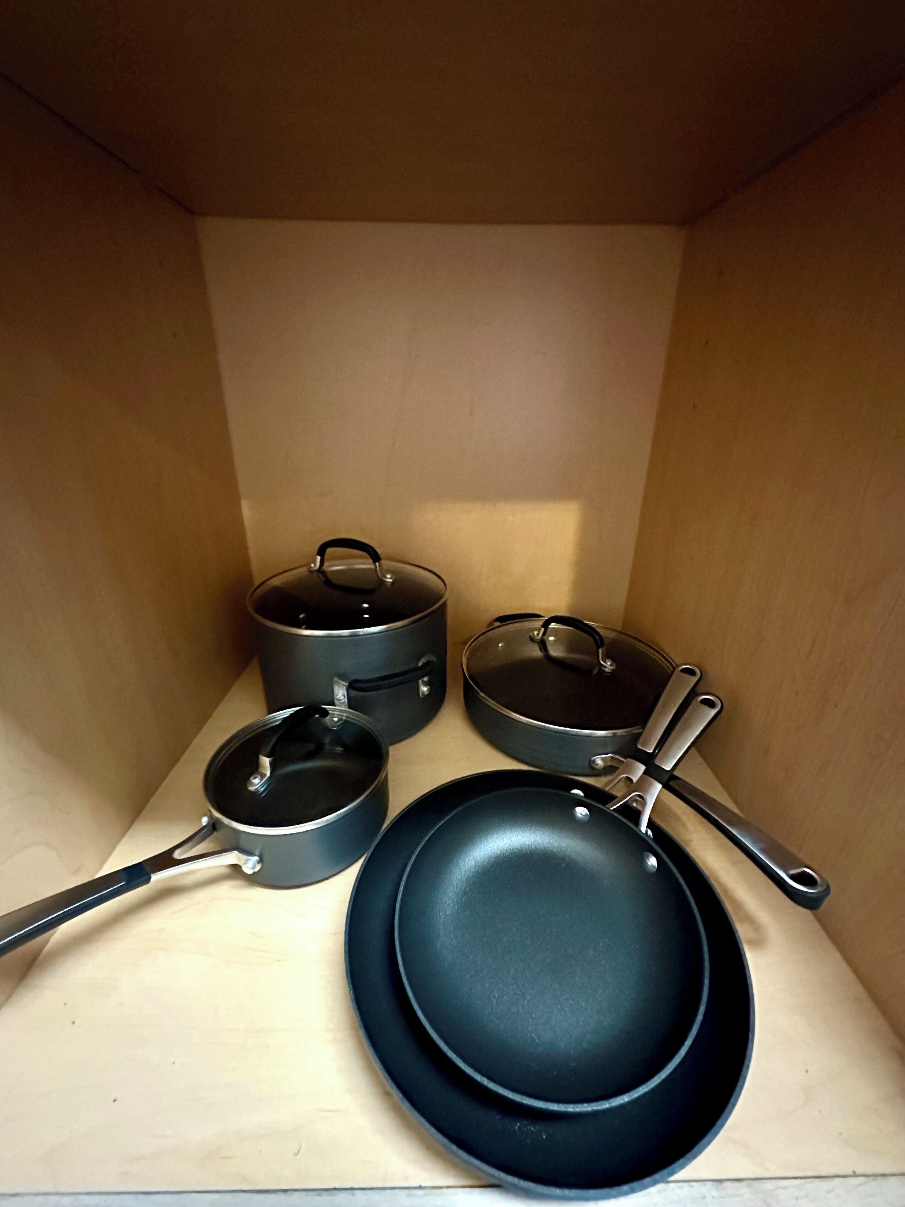 Una serie di pentole da cucina, tra cui una padella, due pentole e un tegame, il tutto contenuto in una scatola di legno.