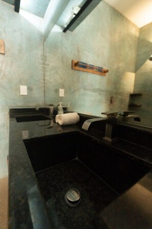 Un bagno moderno con un lavandino nero, uno specchio e un asciugamano.