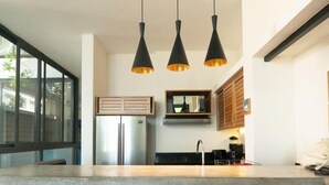 A modern kitchen with a central island, wooden bar stools, and pendant lighting. - Ocean view Apartment PXM (Puerto Escondido)