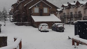 A wooden lodge with a snow-covered roof and a car parked in front. - Cerro Catedral excellent studio apartment (Cerro catedral,Río Negro Province)