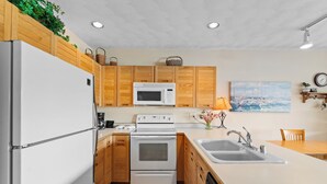 Una cocina moderna con armarios de madera, un refrigerador blanco, un microondas, una estufa y un lavabo.