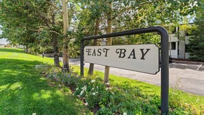 Un letrero que dice 'EAST BAY' con un marco metálico, rodeado de follaje y árboles.