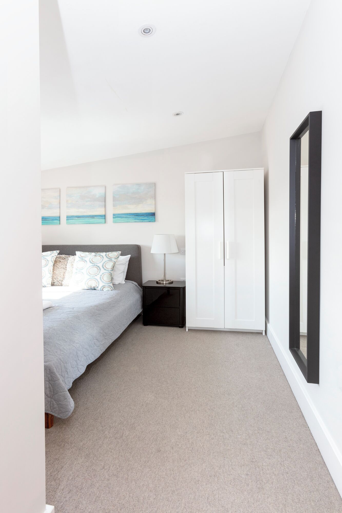 Een slaapkamer met een bed, nachtkastje, garderobe en decoratie aan de muur.
