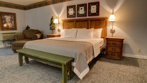 A neatly arranged bedroom with a large bed, bedside tables with lamps, a bench, and a chair. - Angel Fire | Ski Weekend Stay | Hot Tub & Mountain (Angel Fire)