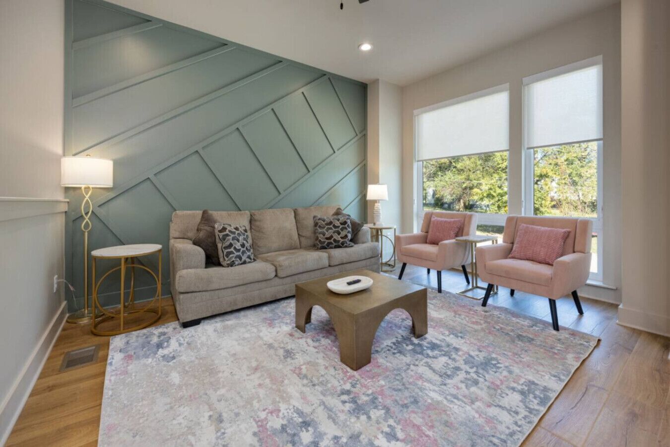Uma sala de estar moderna com um sofá seccional, duas poltronas, uma mesa de centro e um tapete estampado.