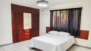 A bedroom with a bed, wooden wardrobe, and an air conditioning unit.