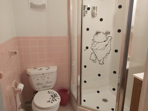A bathroom with a toilet, shower, and pink tiled walls.
