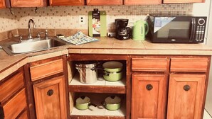Une cuisine avec des meubles de rangement en bois, un évier, un four à micro-ondes et une machine à café.