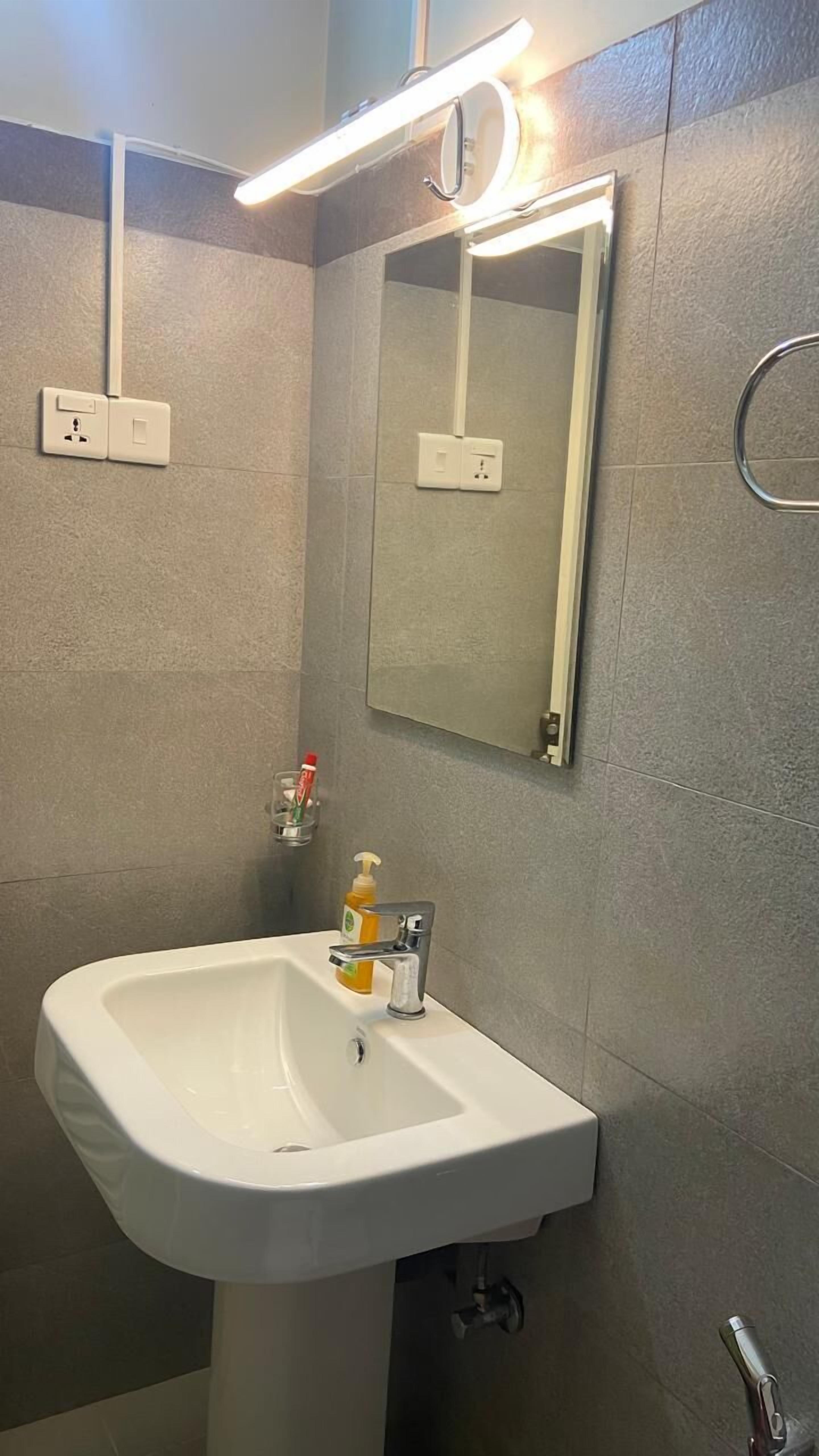 A bathroom with a white sink, a mirror, and a light fixture above it.