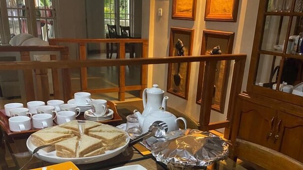A buffet setup with sandwiches, plates, cups, and a teapot. - VISTA HOUSE (Kandy)