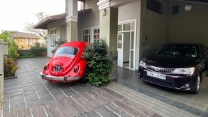 A modern house with a stone facade, a covered driveway, and two cars parked in the garage. - VISTA HOUSE (Kandy)