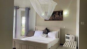 A bedroom with a bed, a window with curtains, a wall-mounted air conditioner, and a decorative painting. - VISTA HOUSE (Kandy)