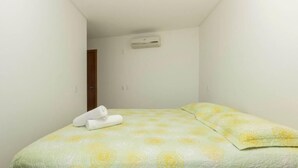 Un letto piccolo e ben rifatto con copripiumino a motivi floreali e due asciugamani arrotolati.