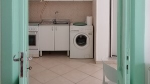 A compact kitchen with white cabinets, a washing machine, and a sink. - Charming 1-bedroom apartment with WiFi, AC in amazing Bari (Bari)