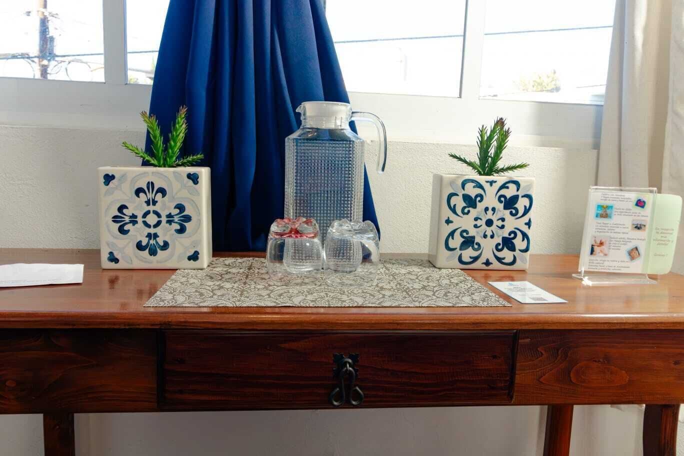 A wooden desk with decorative vases, a pitcher, and a small sign.