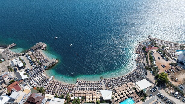An aerial view of a coastal resort with a large beach area, numerous umbrellas, and a swimming pool. - The Collector hotel boutique (Sarandë)