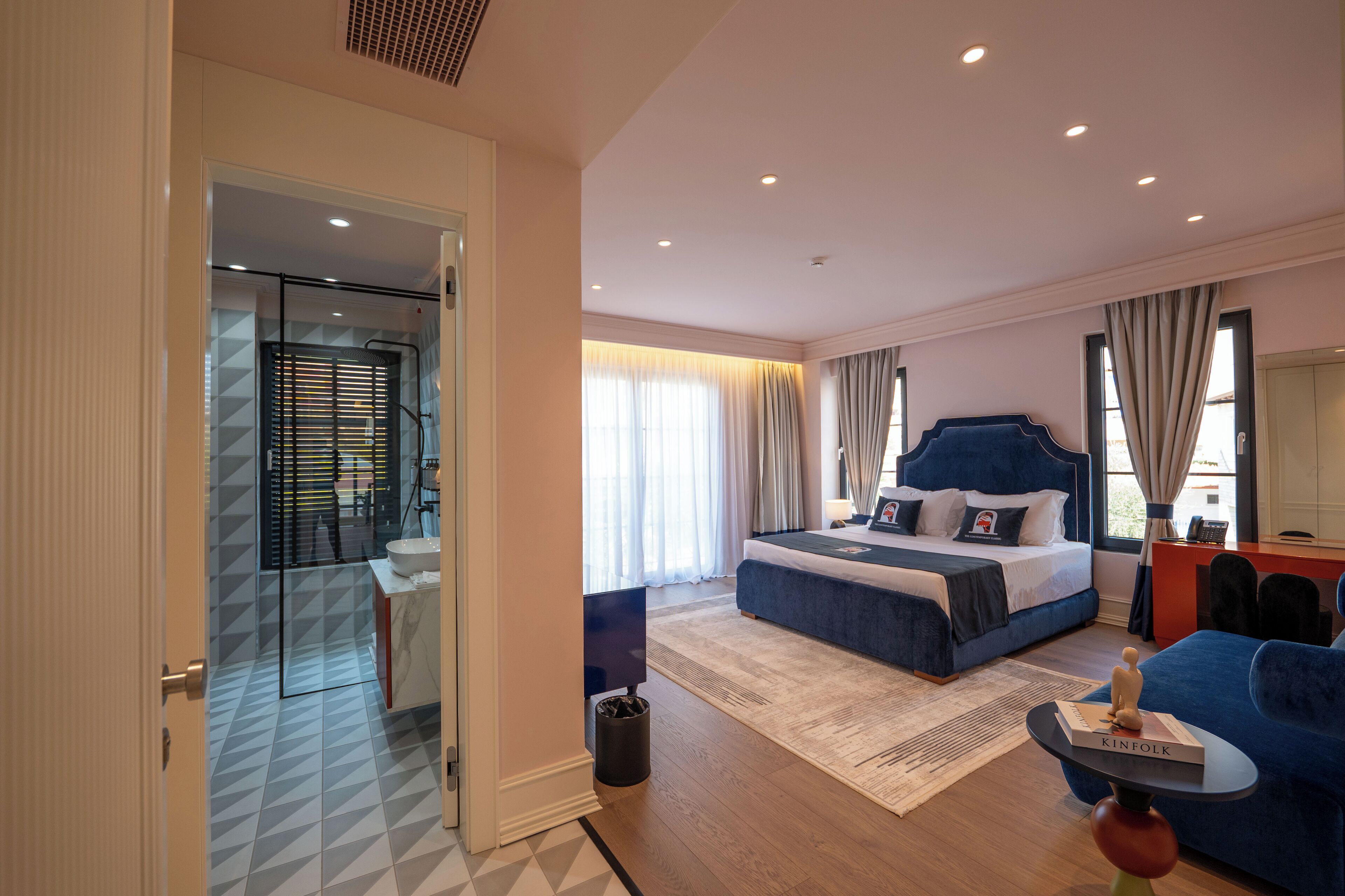 Una habitación de hotel moderna con una cama grande, un escritorio y un área de descanso.