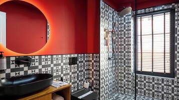 A modern bathroom with a black and white checkered floor, a red accent wall, and a large mirror.