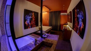 Une salle de bain moderne avec un grand miroir, une baignoire et des œuvres d’art accrochées aux murs.