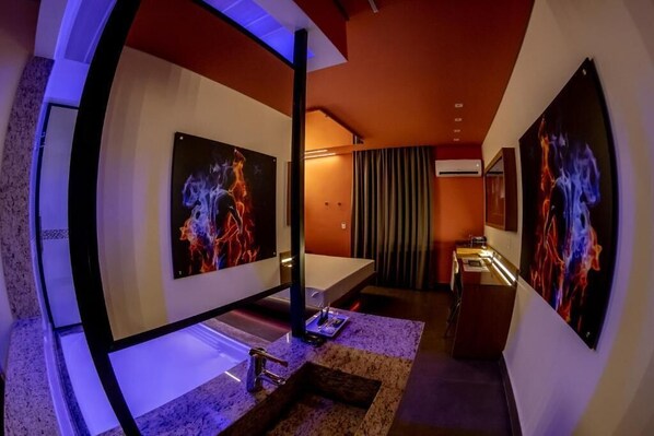A modern bathroom with a large mirror, a bathtub, and artwork on the walls. - Motel Belle (São Paulo)