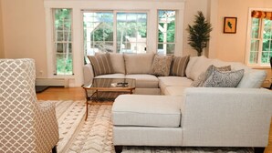 A living room with a sectional sofa, a patterned armchair, and a coffee table. - Large Cozy Home •Songo River•Brandy Pond•Long Lake•Sebago (Naples)
