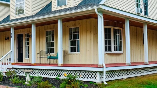 A two-story house with a covered porch, a small front yard, and a mailbox. - Large Cozy Home •Songo River•Brandy Pond•Long Lake•Sebago (Naples)