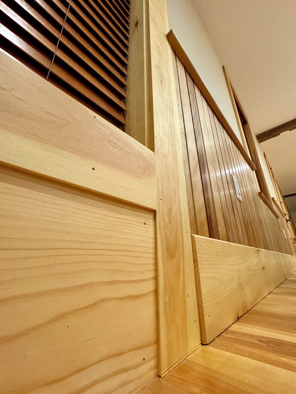 Un escalier en bois avec une main courante et un mur en bois composé de lattes verticales.