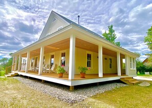 Une maison à deux étages avec un porche couvert, de nombreuses fenêtres et une cheminée.