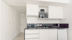 A modern kitchen with white cabinets, a black countertop, and a white refrigerator. - Comfortable stylish studio in Recoleta (Ciudad Autonoma de Buenos Aires)