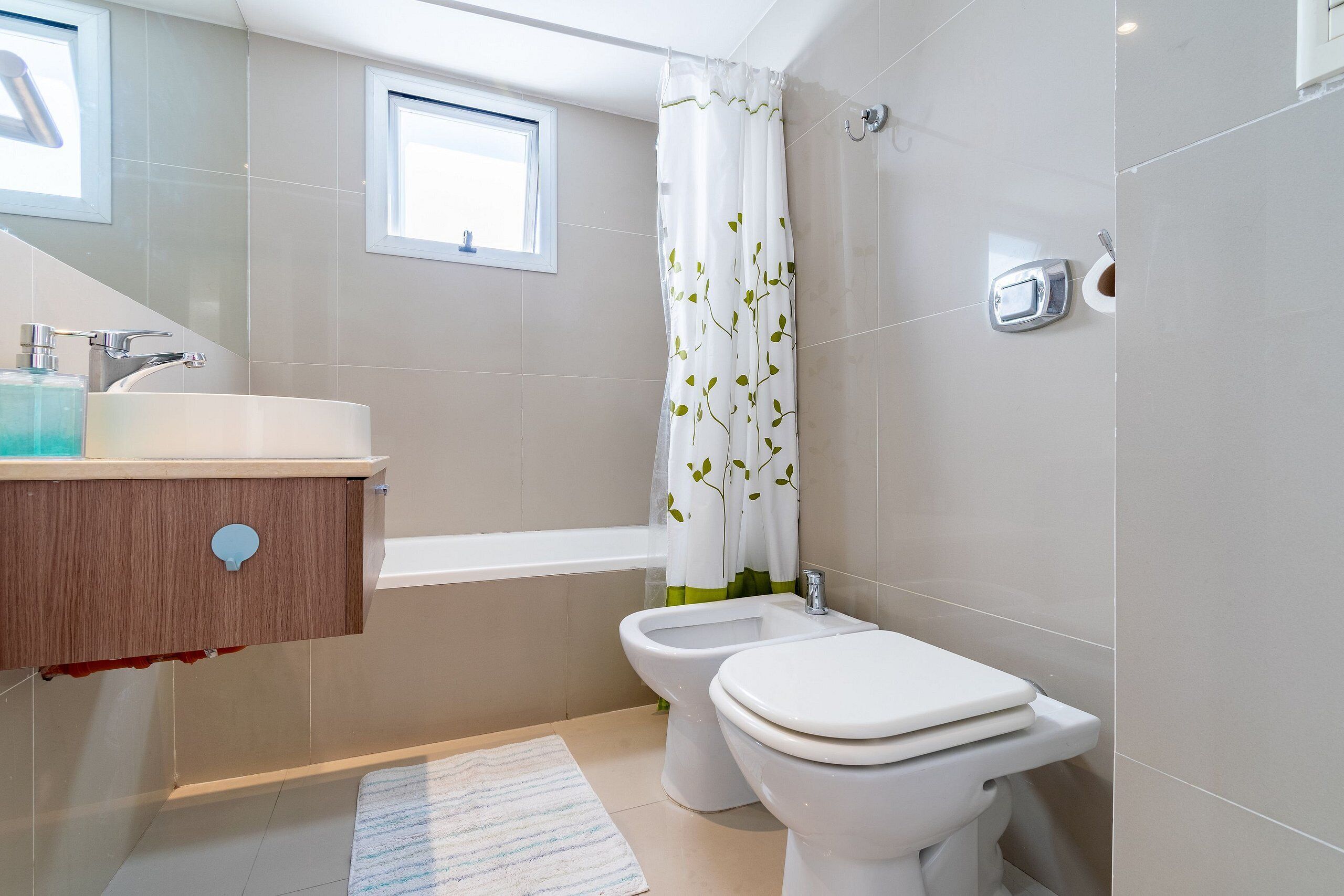 A bathroom with a bathtub, a bidet, a toilet, a sink, and a window.
