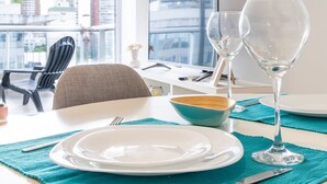 A dining table set with a plate, two wine glasses, and a bowl, with a teal placemat.
