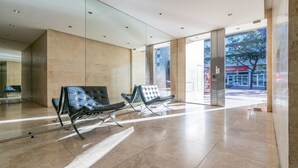 A spacious lobby with two leather chairs, a glass wall, and a view of the outside.