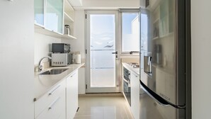 A modern kitchen with white cabinets, a stainless steel refrigerator, and a coffee maker.
