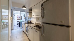 Une cuisine moderne dotée d’appareils électroménagers en acier inoxydable, d’un plan de travail en granit et d’un coin repas visible à travers une porte ouverte.