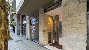 A building entrance with a stone facade, glass doors, and a no parking sign.