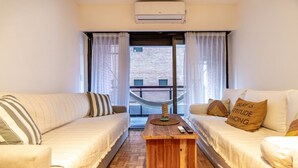 Ein Zimmer mit zwei Sofas, einem Holztisch und Blick auf einen Balkon mit einer Hängematte.