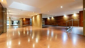 Eine geräumige Lobby mit glänzendem Boden, einer Treppe und Holzvertäfelungen an den Wänden.