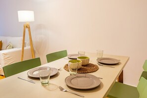 A dining table set with plates, glasses, and cutlery, surrounded by green chairs. - Spacious apartment in Palermo (caba)