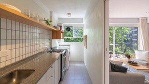 Eine moderne Küche mit Einbauherd, Spüle und einem Fenster mit Blick auf einen Balkon.