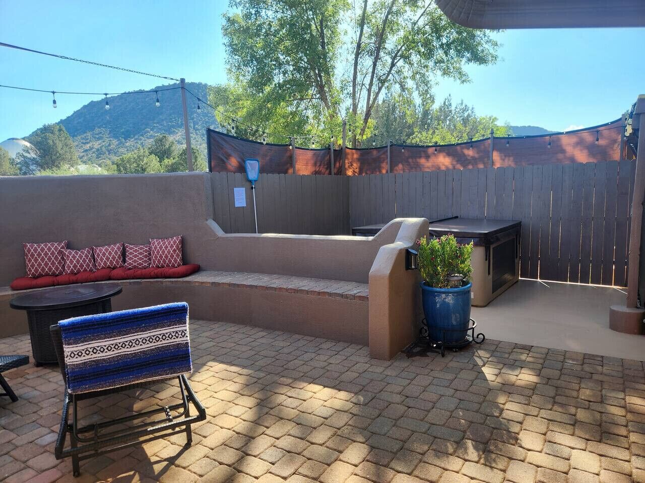 Une terrasse extérieure dotée d’un espace salon intégré, d’un barbecue et de plantes en pot.