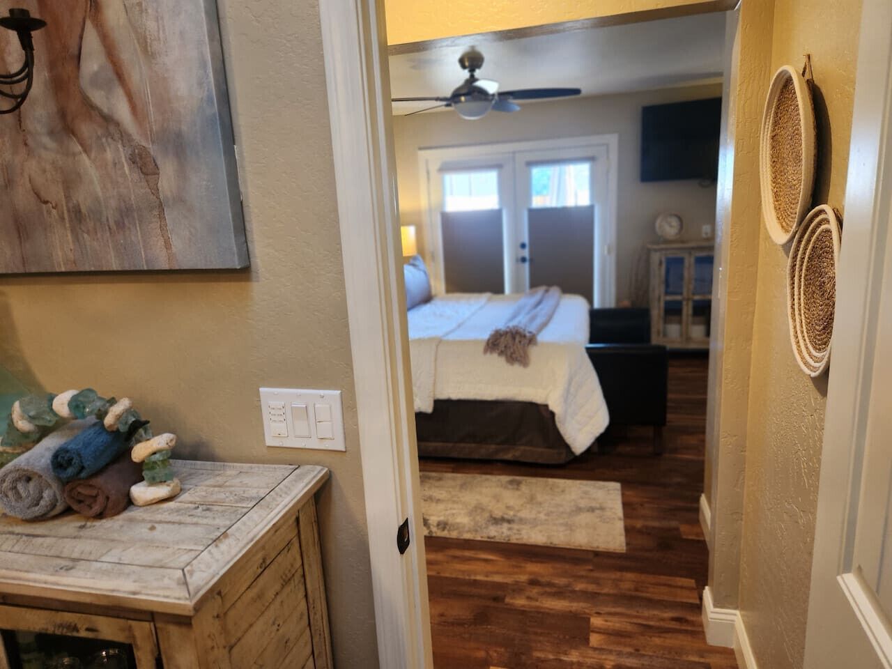 Une chambre à coucher avec un lit, un ventilateur de plafond et une vue sur le salon.